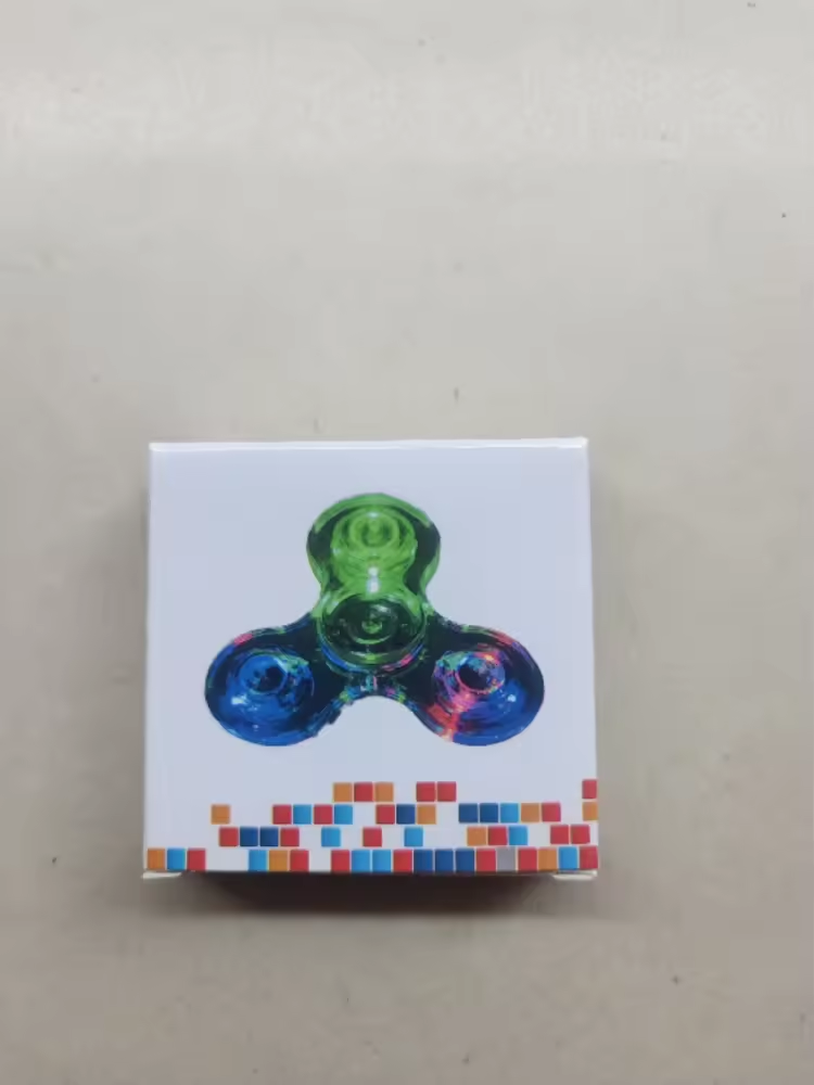 Fidget spinner in a box with colorful design on a beige background