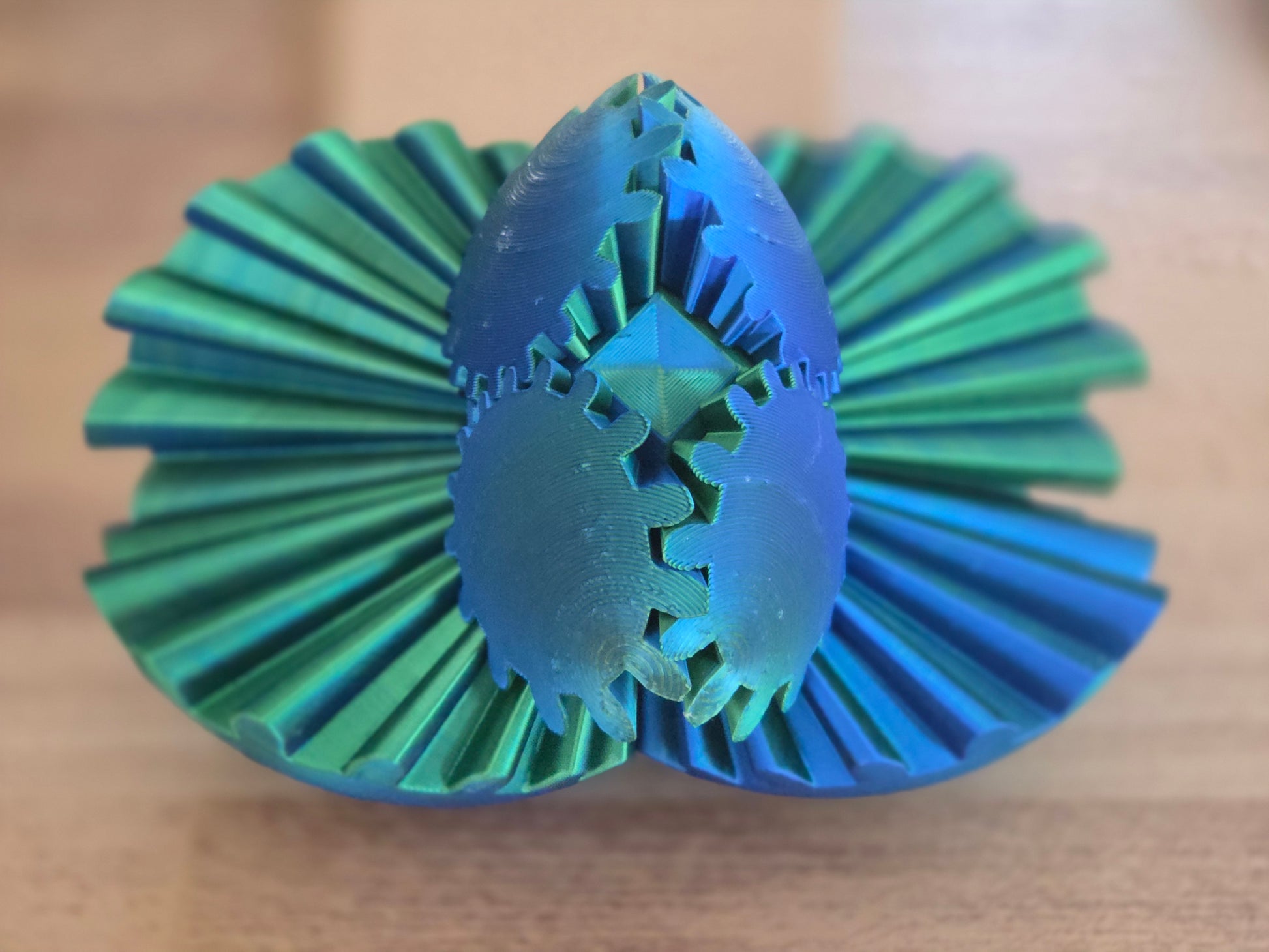 Green and blue plastic fidget spinner with geometric design on a wooden surface