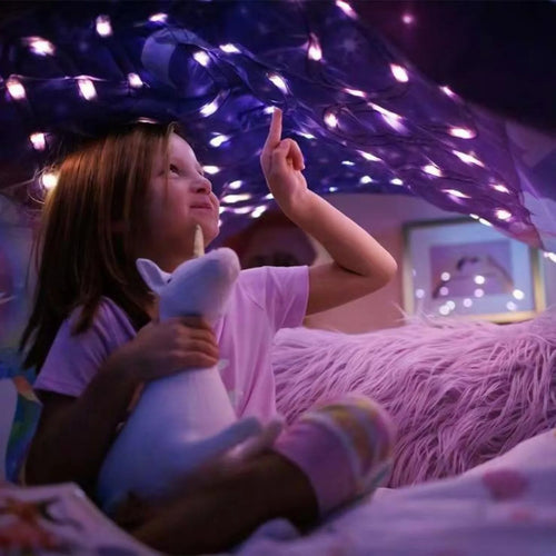 Child lying under starry light bed tent