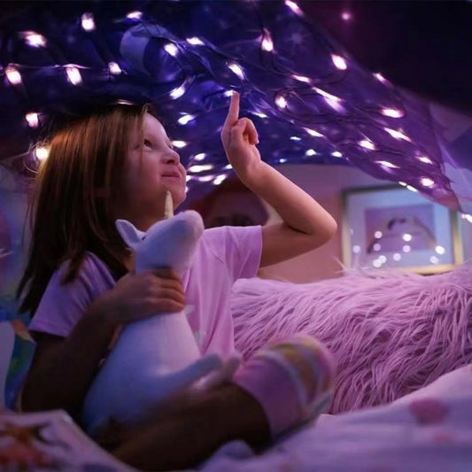 Child lying under starry light bed tent