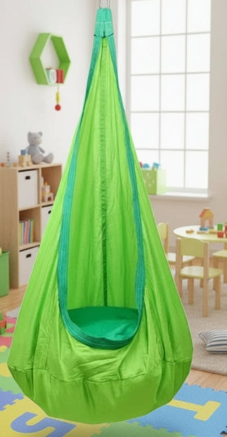 Green children's swing in a room with toys and furniture.