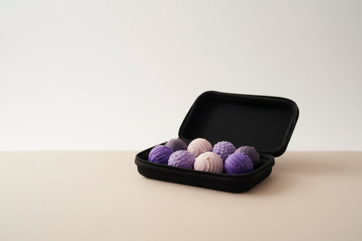 Black case with purple and pink textured balls on a light wooden floor.