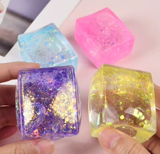 Colorful glittery resin cubes held by a hand on a light background