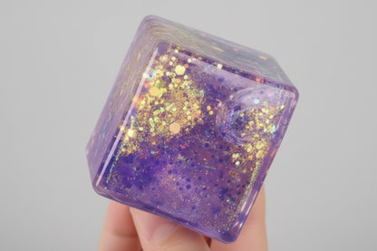 Glittery, multicolored fidget cube held in a hand 
