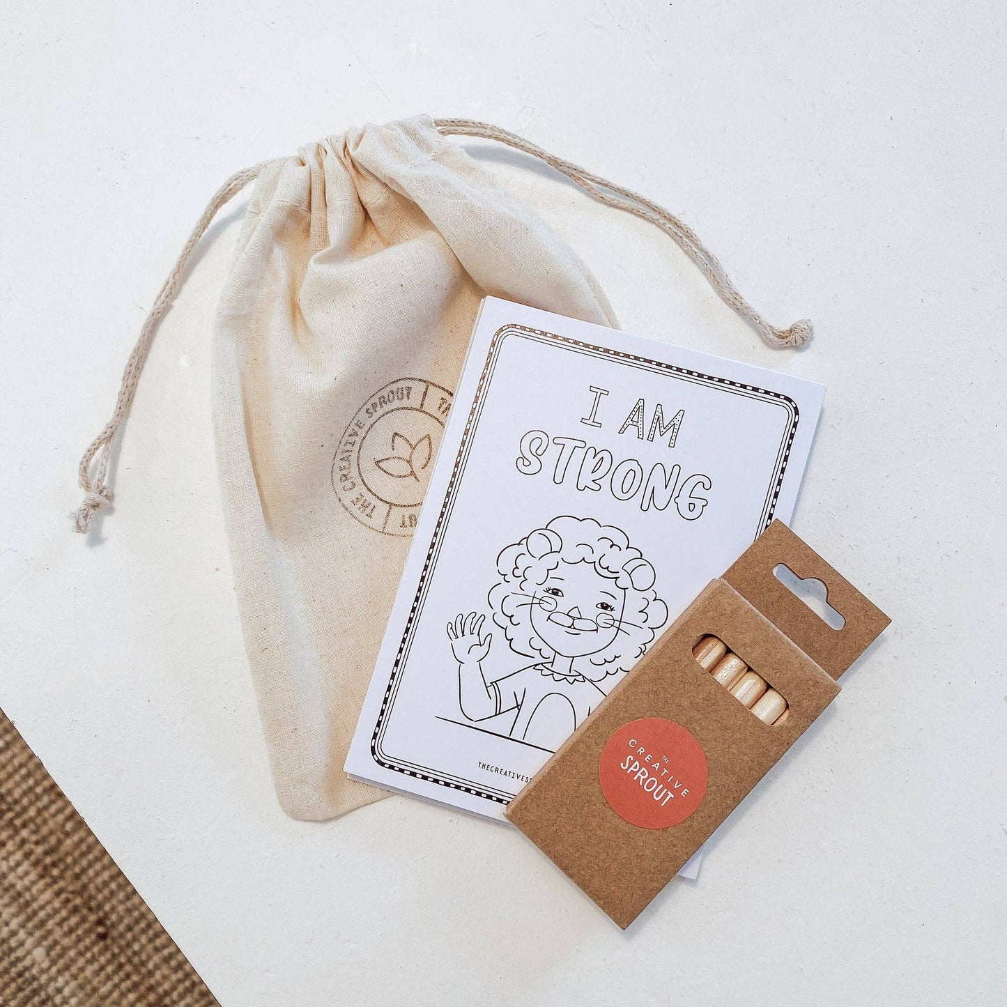 Educational kit with 'I AM STRONG' card, wooden sticks, and drawstring bag on a white background