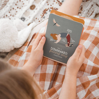 Person holding a yoga pose book on a checkered blanket
