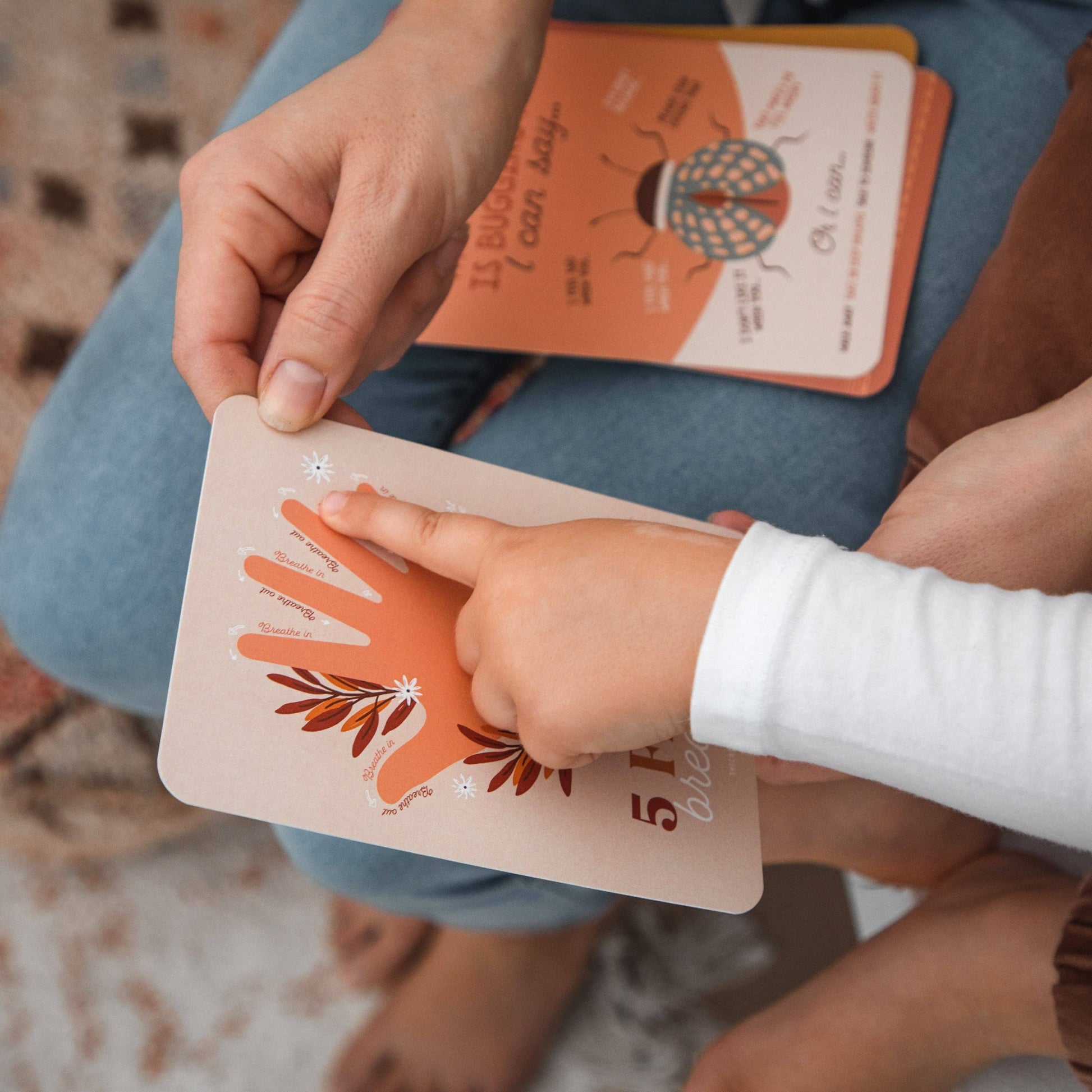 Child's hand holding a small card with a hand design, placed on a larger card with a similar design.