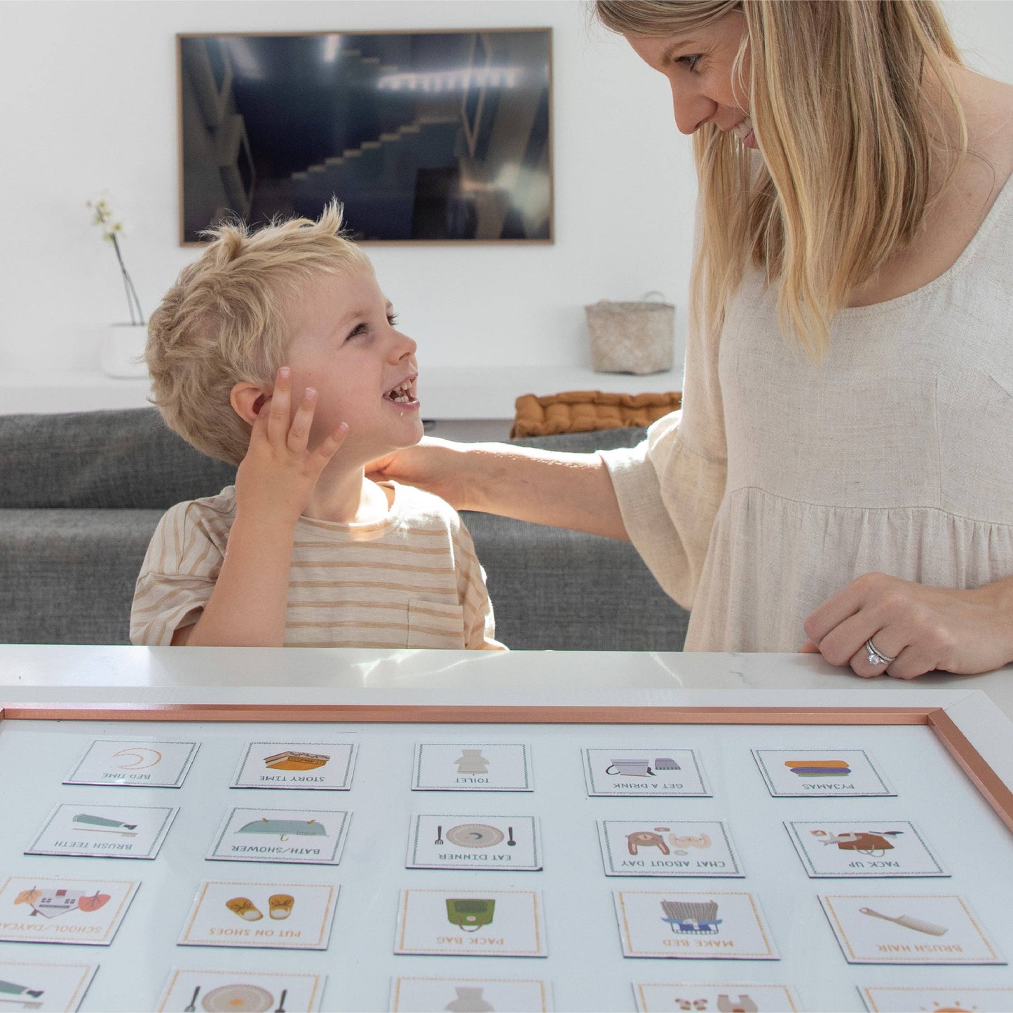 Woman and child interacting with educational cards on a table in a living room.