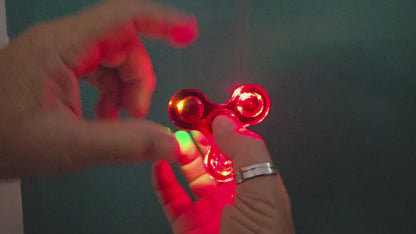 LED fidget spinner with colourful lights spinning in a dark setting.