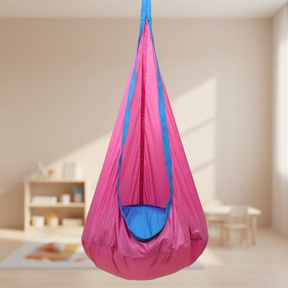 Pink and blue hanging sensory chair on a wooden deck with outdoor furniture and plants in the background.