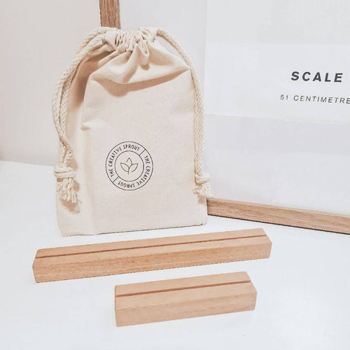 Set of wooden measuring sticks with a drawstring bag on a light background