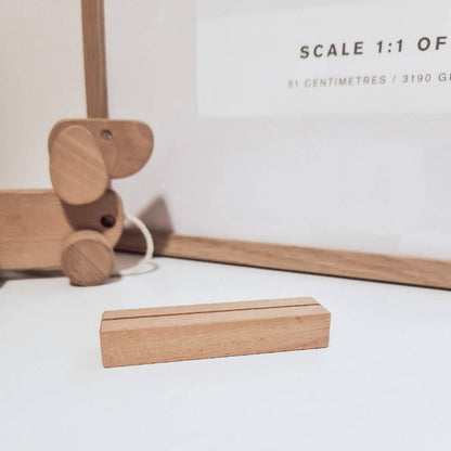 Wooden toy elephant and block on a white surface with measurement text in the background